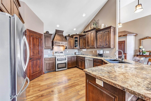 kitchen featuring pendant lighting, light wood-type flooring, custom exhaust hood, stainless steel appliances, and a sink