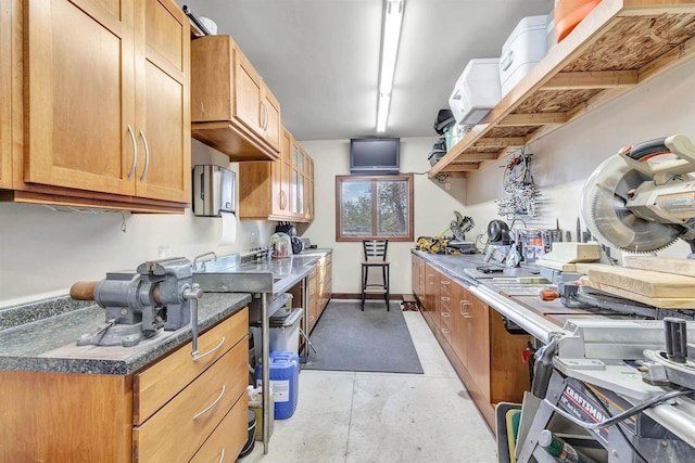 kitchen featuring baseboards, dark countertops, and concrete flooring