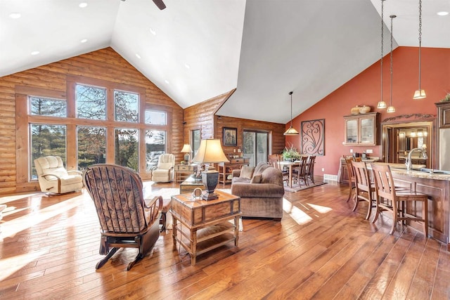 living area featuring light wood-style floors, baseboards, and high vaulted ceiling