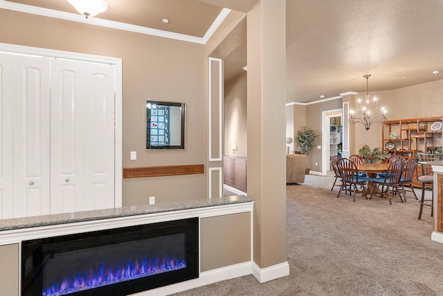 interior space with carpet flooring, baseboards, a chandelier, and ornamental molding