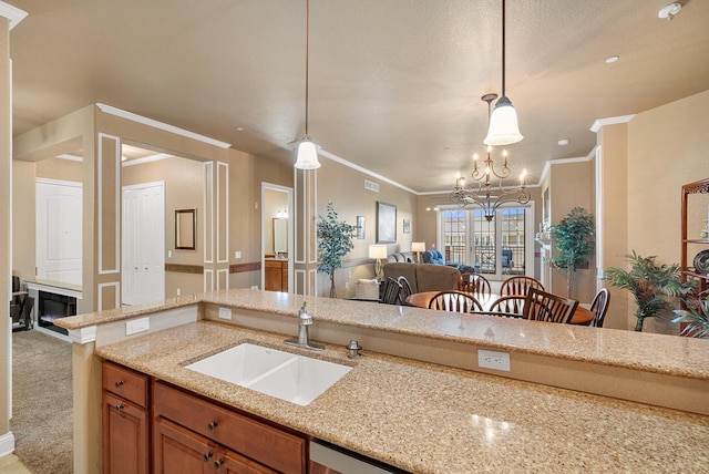 kitchen featuring brown cabinetry, pendant lighting, light stone counters, and a sink