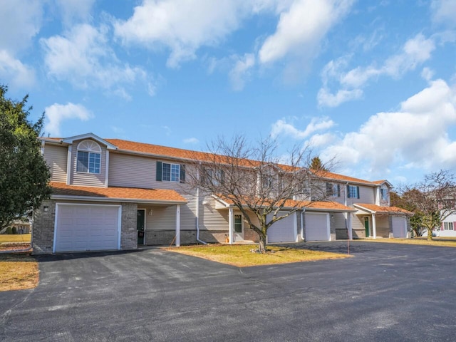 townhome / multi-family property featuring aphalt driveway, a garage, and brick siding