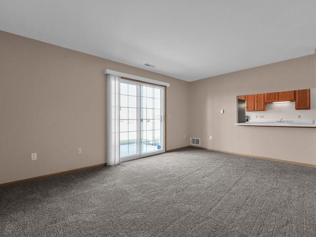 unfurnished living room with visible vents, baseboards, and carpet