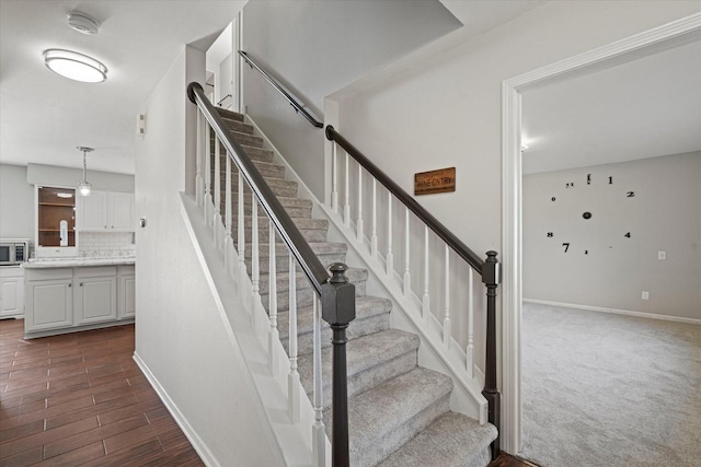 staircase featuring baseboards, wood finished floors, and carpet flooring