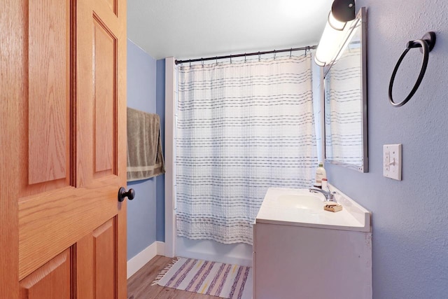 bathroom featuring shower / tub combo, wood finished floors, vanity, and a textured wall