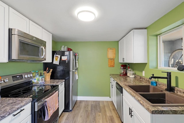 kitchen featuring a sink, light wood-style floors, appliances with stainless steel finishes, and white cabinetry