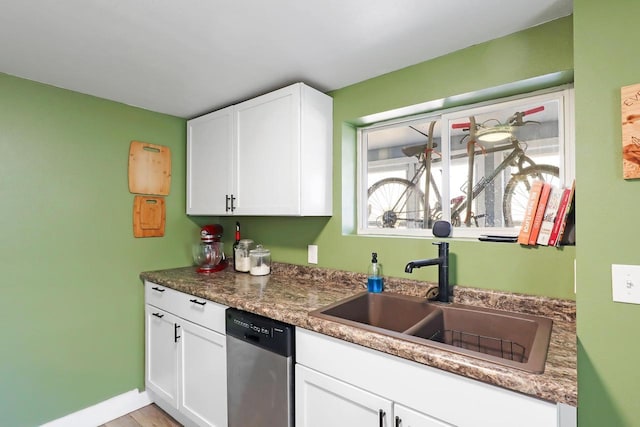 kitchen featuring a sink, dark countertops, dishwasher, and white cabinetry