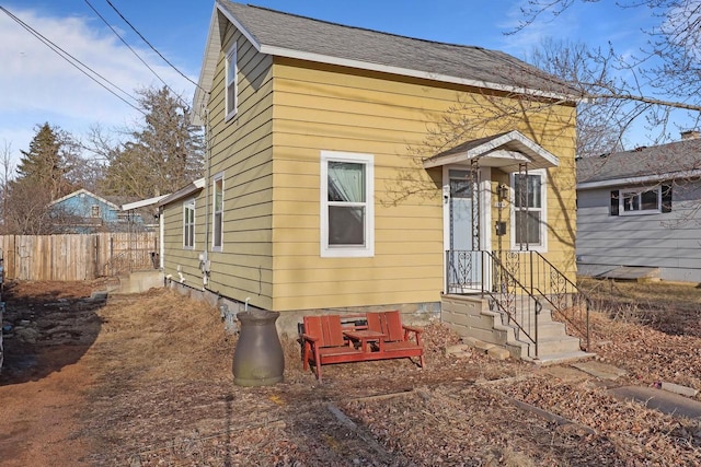 view of front of house featuring fence and a shingled roof