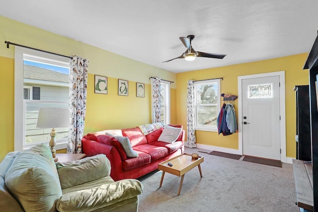 living area featuring baseboards, a ceiling fan, and carpet flooring