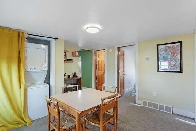 dining room featuring baseboards, visible vents, carpet floors, and stacked washing maching and dryer