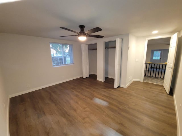 unfurnished bedroom with baseboards, recessed lighting, ceiling fan, dark wood-type flooring, and multiple closets