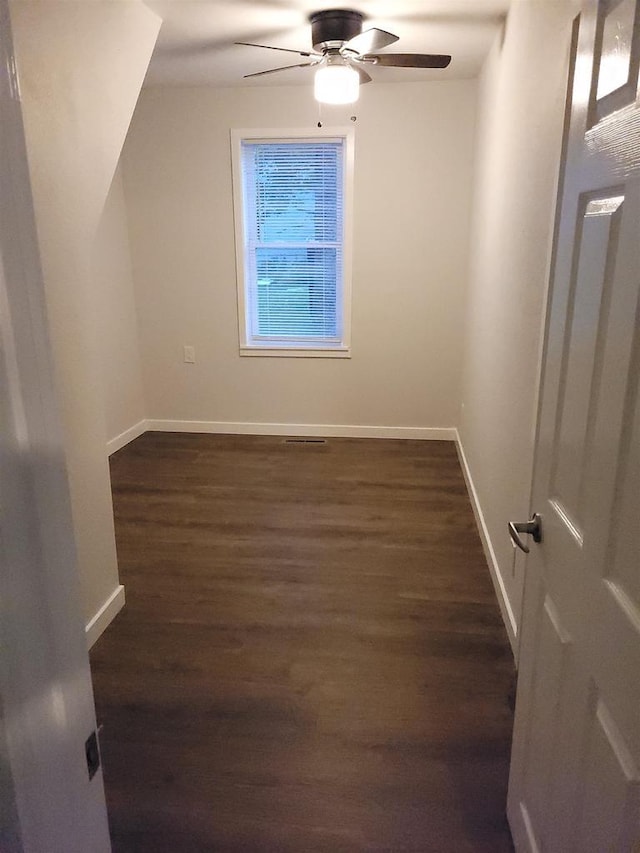 additional living space featuring baseboards, dark wood-type flooring, and ceiling fan