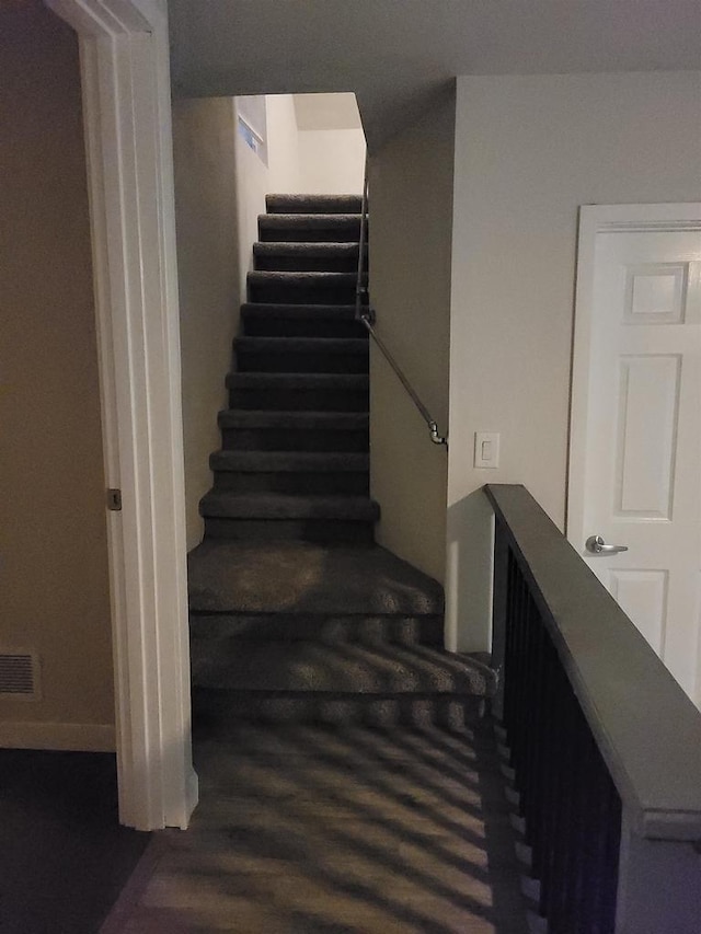 stairway featuring visible vents and wood finished floors