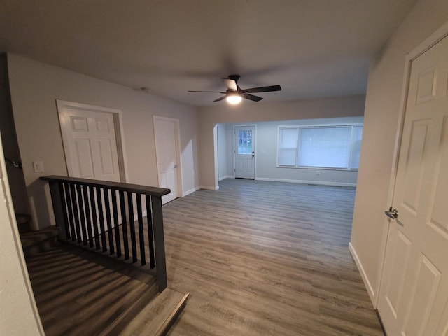 interior space with a ceiling fan, wood finished floors, and baseboards