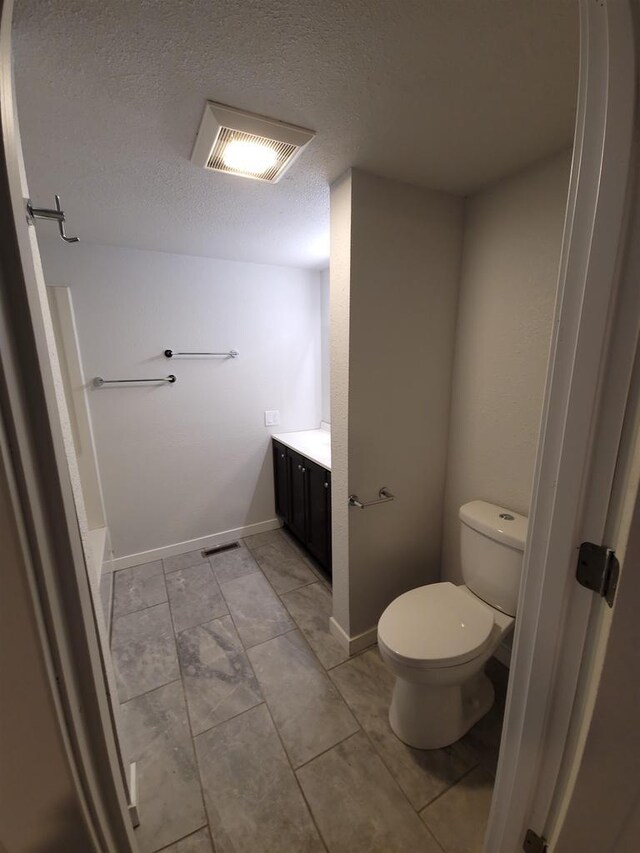 bathroom featuring vanity, toilet, visible vents, and a textured ceiling