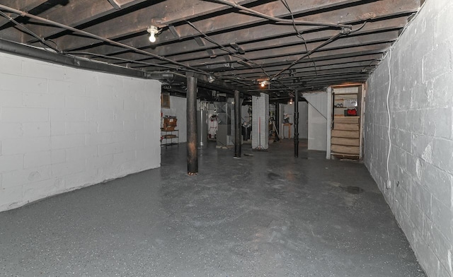 unfinished basement with stairs, concrete block wall, and water heater