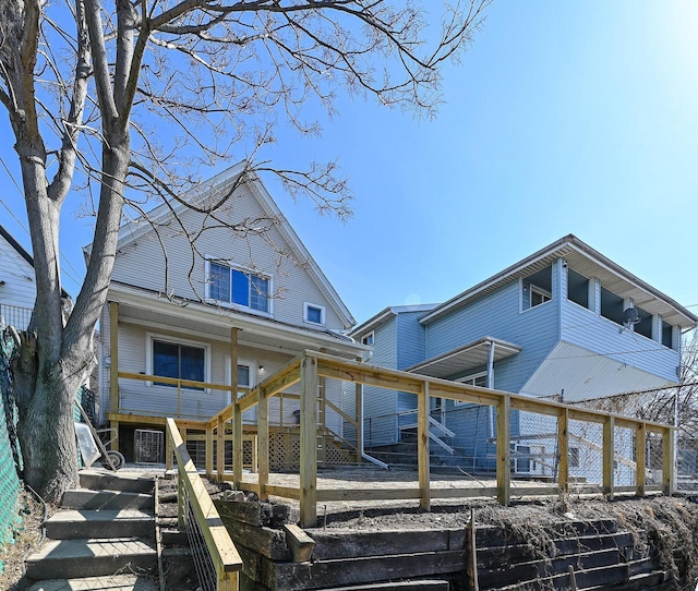 rear view of property featuring stairway, a wooden deck, and fence