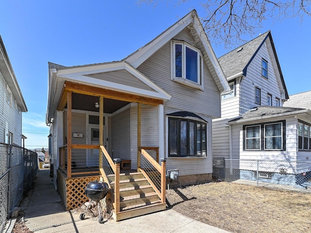 view of front of property with covered porch, a shingled roof, and fence