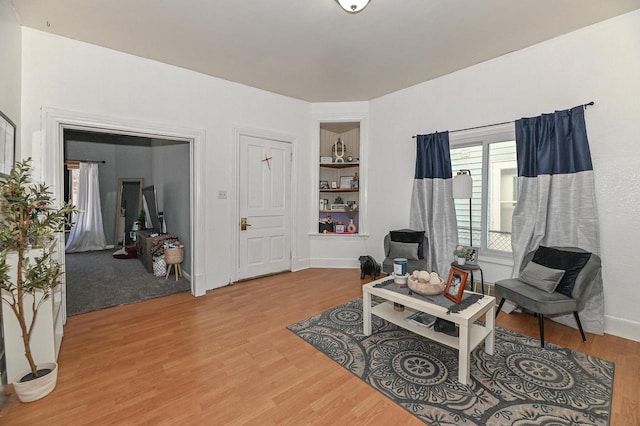 living area featuring built in features, wood finished floors, and baseboards