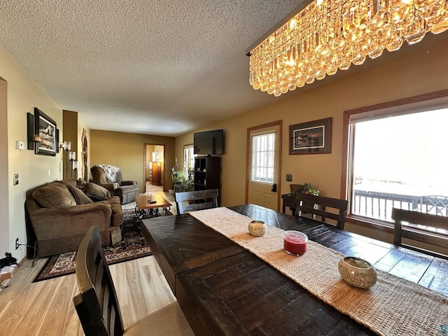 dining room featuring a textured ceiling, a chandelier, and light wood finished floors