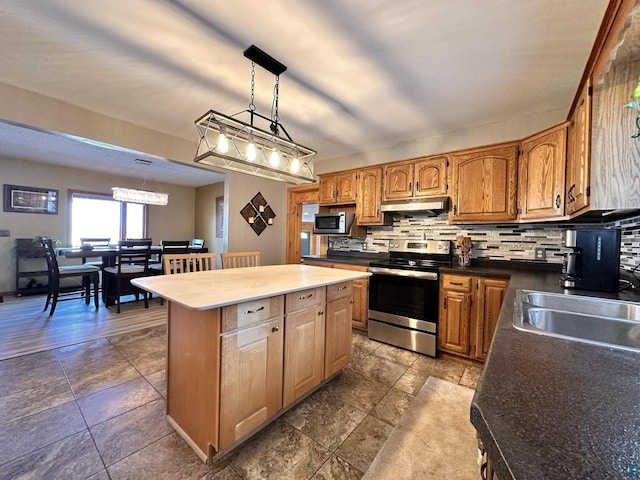 kitchen featuring a sink, decorative backsplash, stainless steel appliances, under cabinet range hood, and a center island