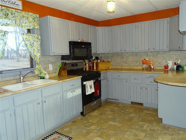 kitchen featuring decorative backsplash, stainless steel gas stove, black microwave, and a sink