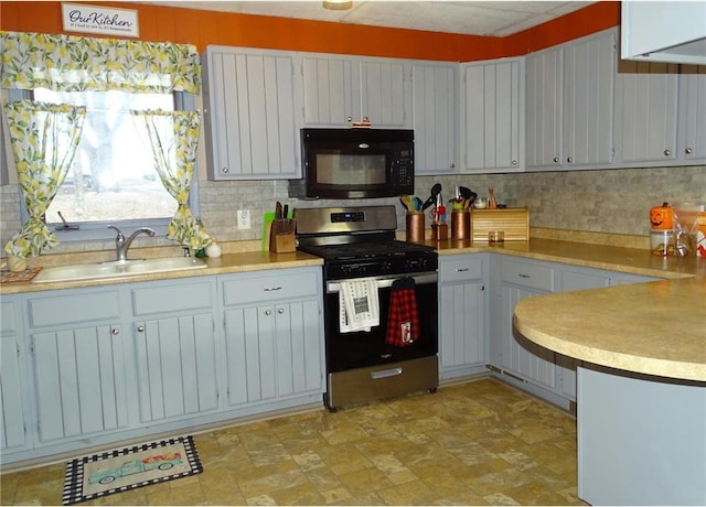 kitchen featuring stainless steel gas range, a sink, decorative backsplash, light countertops, and black microwave