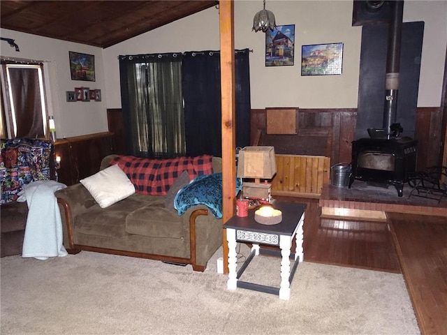 living area featuring a wood stove, wooden ceiling, wainscoting, and vaulted ceiling