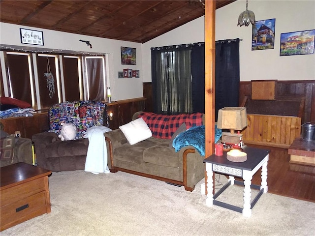 living room featuring lofted ceiling, wooden walls, wood ceiling, and a wainscoted wall