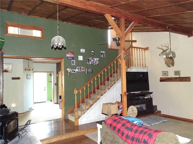 living room with beamed ceiling, stairs, a wood stove, and wood finished floors