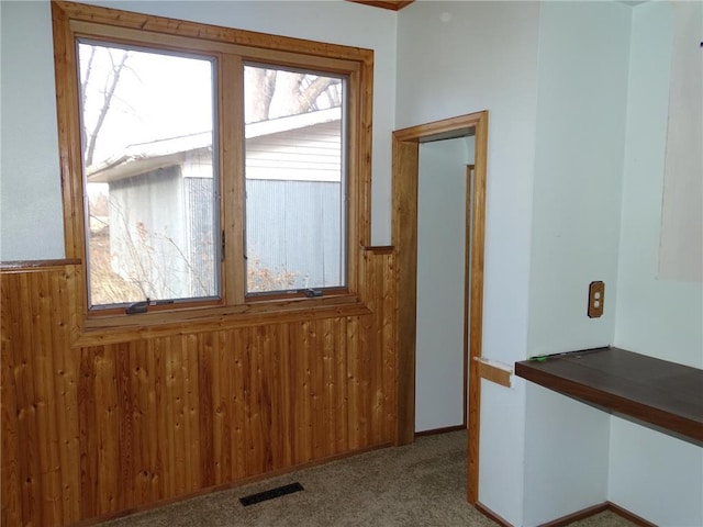 doorway with visible vents, a wainscoted wall, carpet, and wood walls