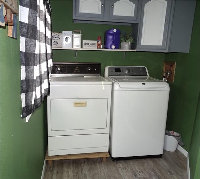 washroom with cabinet space, washing machine and dryer, and wood finished floors