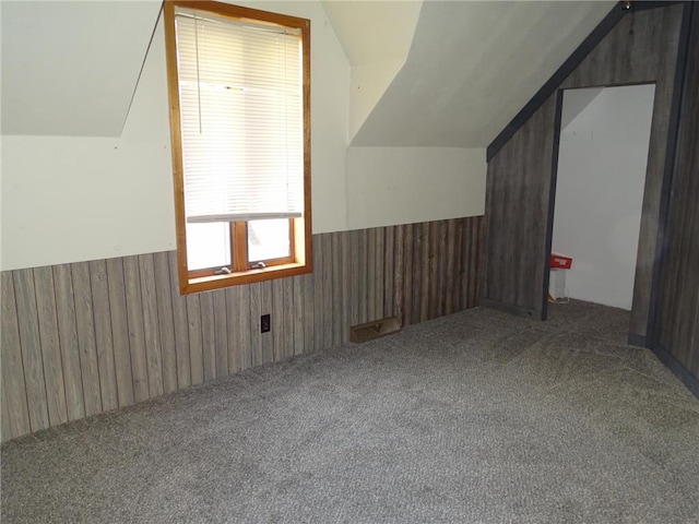 bonus room featuring carpet flooring, lofted ceiling, wood walls, and wainscoting