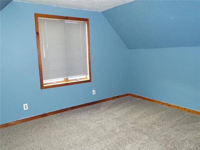 additional living space with baseboards, carpet flooring, and vaulted ceiling