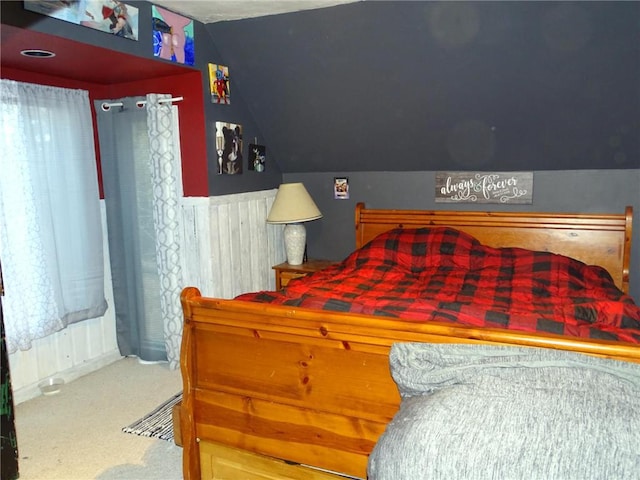 carpeted bedroom with wainscoting and lofted ceiling