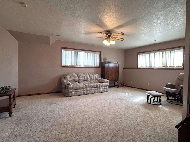 carpeted living room with a textured ceiling, baseboards, and ceiling fan