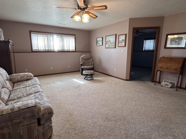 carpeted living area with a textured ceiling, baseboards, visible vents, and ceiling fan