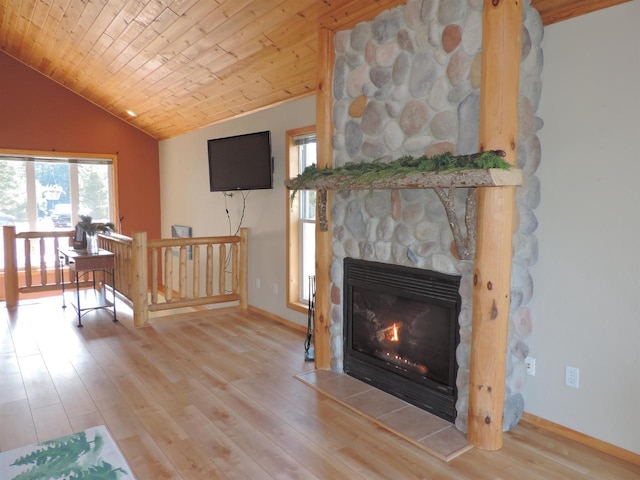 living area featuring wood finished floors, baseboards, a stone fireplace, vaulted ceiling, and wooden ceiling