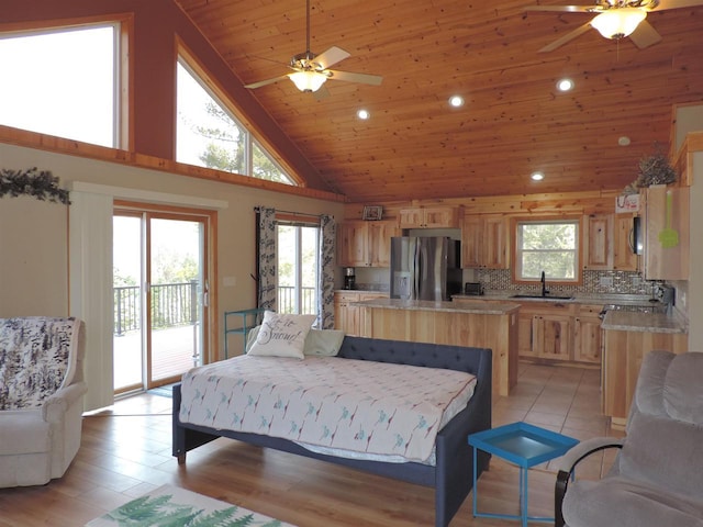 bedroom featuring access to outside, multiple windows, stainless steel refrigerator with ice dispenser, and a sink