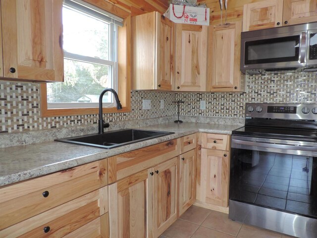 kitchen featuring a sink, appliances with stainless steel finishes, light brown cabinets, and light countertops