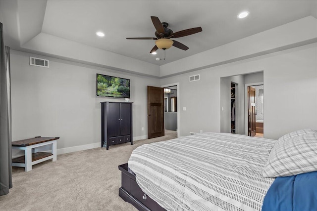 bedroom featuring a tray ceiling, visible vents, baseboards, and light colored carpet