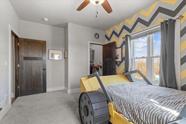 carpeted bedroom with a walk in closet, a ceiling fan, a closet, wallpapered walls, and baseboards