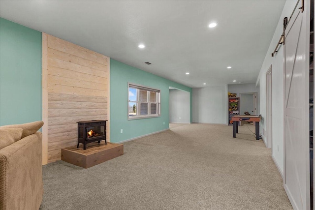 carpeted living area with a wood stove, recessed lighting, visible vents, and baseboards