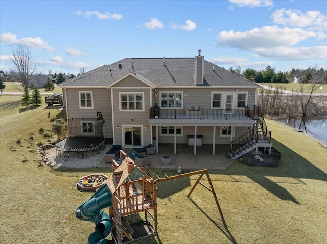 rear view of house with a chimney, stairs, a playground, a patio area, and a lawn