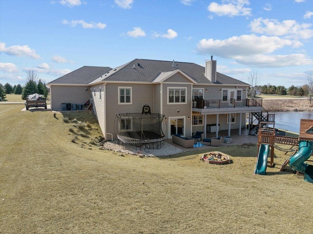 rear view of property with a lawn, a chimney, a playground, and a patio