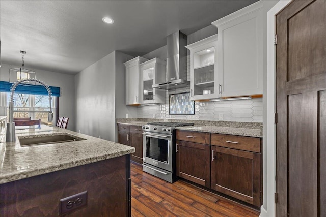 kitchen with backsplash, dark wood-style floors, wall chimney exhaust hood, white cabinets, and stainless steel range with gas stovetop