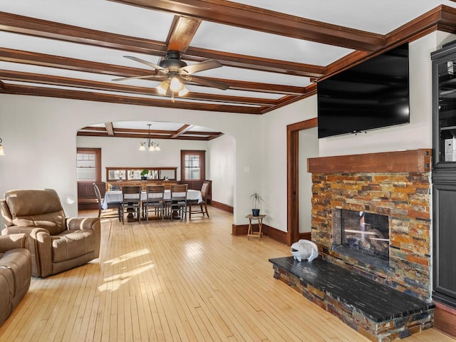 living room with arched walkways, light wood-style floors, and beam ceiling