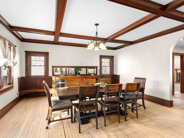 dining area featuring baseboards, beam ceiling, light wood-style flooring, an inviting chandelier, and arched walkways