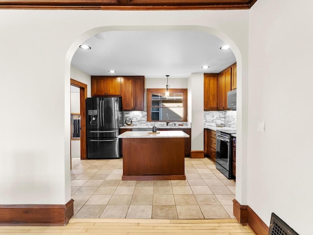 kitchen featuring black fridge with ice dispenser, a center island, arched walkways, stainless steel electric range, and light countertops