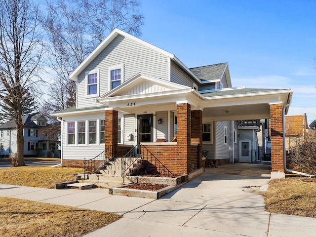 view of front of house featuring concrete driveway, brick siding, and roof with shingles